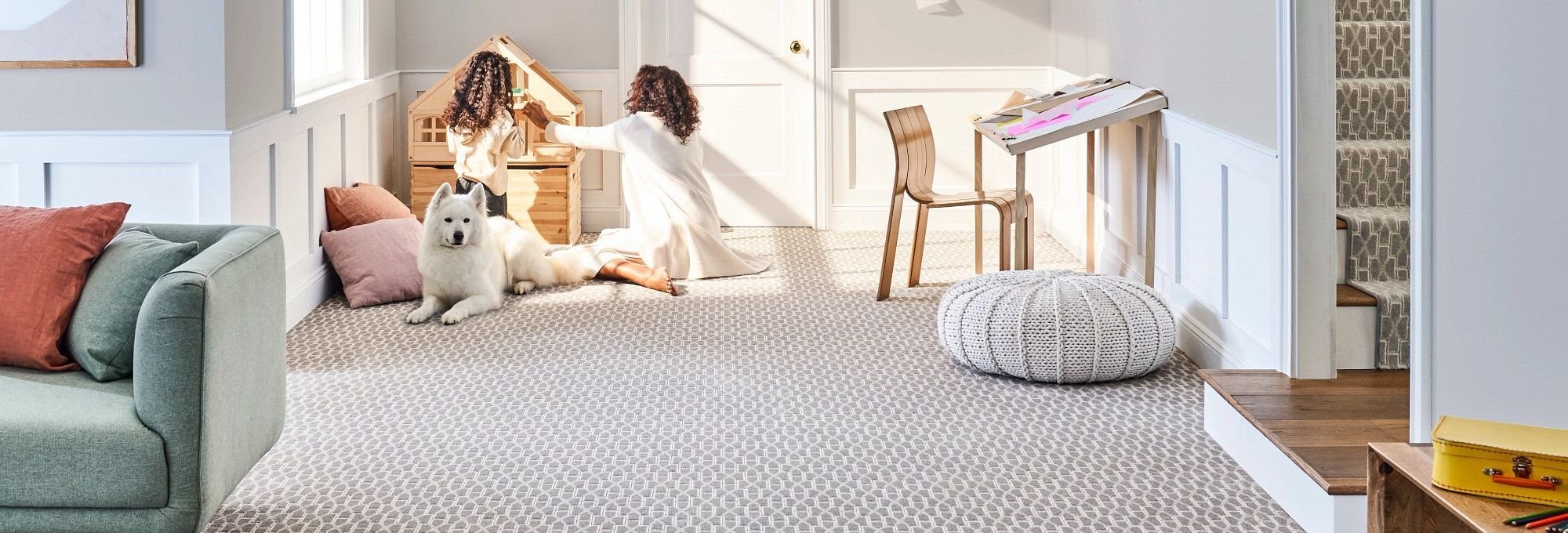 Excellent and loyal dog stands watch while mother and daughter play in a living room with patterned carpet from 180 Degree Floors in the Nashville, TN area